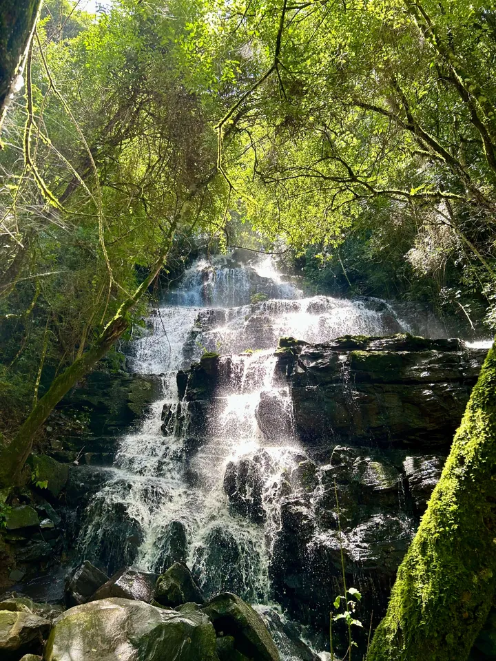 A cascata da Lumine descendo pelas pedras, entre a mata